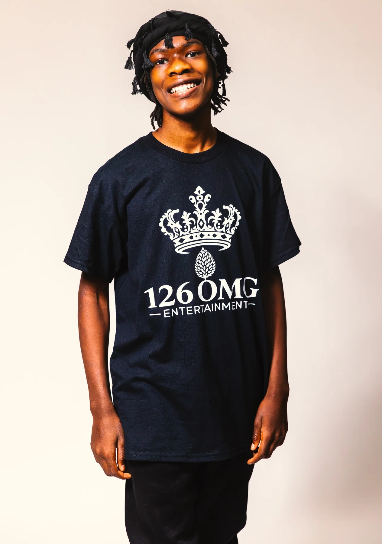 A smiling son in a 126 OMG Entertainment shirt and black trousers